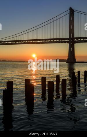 Sole che sorge sul Bay Bridge Foto Stock