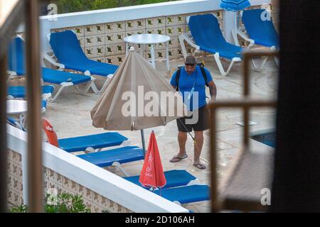 La foto del 2020 luglio mostra un membro del personale di un hotel Ibiza nelle Isole Baleari che disinfetta i lettini e le sedie a sdraio intorno ad una piscina durante l'epidemia di Coronavirus. Foto Stock
