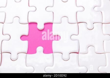 Puzzle bianco con un pezzo mancante e rosa Sfondo - immagine Foto Stock