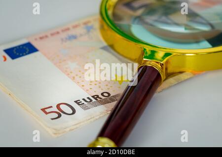 Un fascio di denaro dell'Unione europea con una lente d'ingrandimento, banconote in euro fity, la più alta denominazione. Concetto di fluttuazione della valuta europea Foto Stock