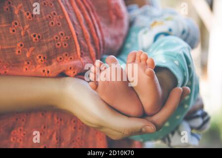 I piedi del bambino nelle mani della mamma. Wonam che tiene il bambino Foto Stock