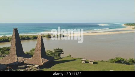 Tetti ornati di closeup case nel villaggio tradizionale indonesiano sulla costa di sabbia oceano meraviglioso paesaggio naturale sulla spiaggia di sabbia di mare dell'isola di Sumba, Indonesia, Asia. Drone shot cinematografico con luce morbida Foto Stock