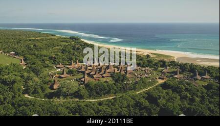 Villaggio aereo tradizionale con tetti ornati case sulla costa di sabbia del mare. Attrazione turistica indonesiana con paesaggio verde sulla baia dell'oceano. Luogo di riferimento cinematografico dell'isola di Sumba, in Asia Foto Stock