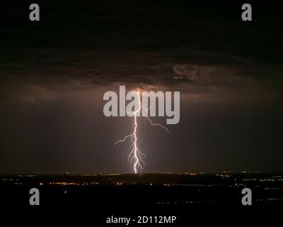 Inquietante scenario di fulmine colpire una città in un notte buia Foto Stock