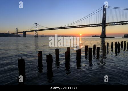 Sole che sorge sul Bay Bridge Foto Stock