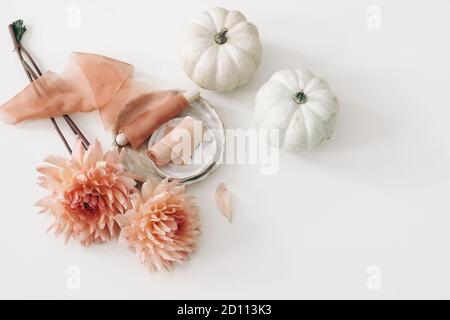 Composizione di nozze floreali d'autunno, vita morta femminile. Fiori di dahlia rosa, nastri di seta e zucche bianche isolate sullo sfondo della tavola. Caduta Foto Stock
