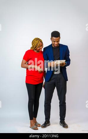 un giovane bell'uomo d'affari africano che ha messo il suo collega attraverso as le spiega che cosa è nel tablet contiene Foto Stock