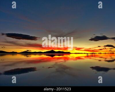 Spettacolare tramonto luminoso sulle saline di Salar de Uyuni, Bolivia. Cielo scenografico al tramonto. Impressionante cielo nuvole simmetria. Riflessione in acqua. Foto Stock