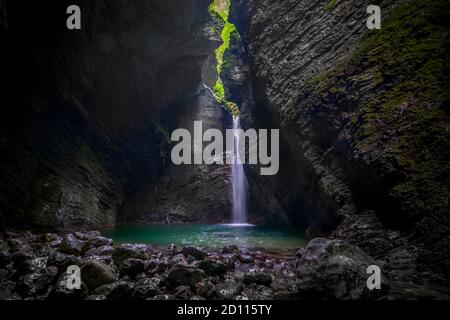 Bella cascata nella grotta scura. Cascata di Kozjak nella valle di Soca, Slovenia. Foto Stock