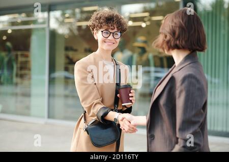 Due giovani colleghi o partner commerciali si scuotono le mani dopo negoziazione Foto Stock
