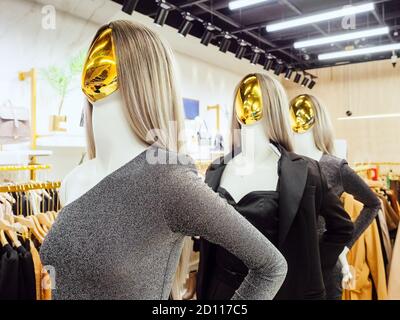 Manichini astratti femminili con facce dorate in stativo da sera in boutique Foto Stock