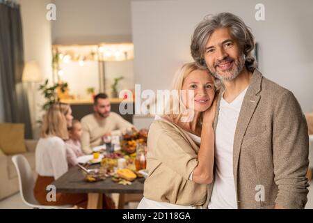 Allegra coppia matura che si trova di fronte alla macchina fotografica contro il pranzo famiglia Foto Stock