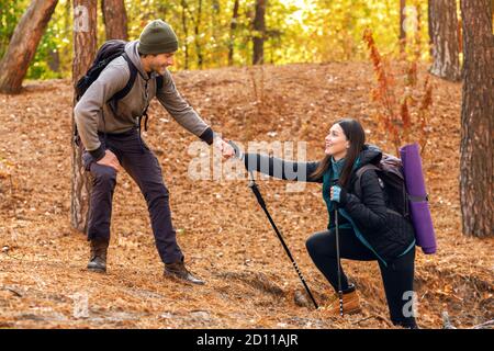 Bell'escursionista che aiuta la sua ragazza in salita in foresta Foto Stock