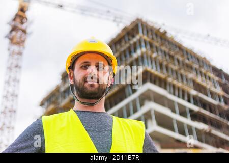 Un ingegnere che posa di fronte alla costruzione di un edificio è funzionamento di Foto Stock