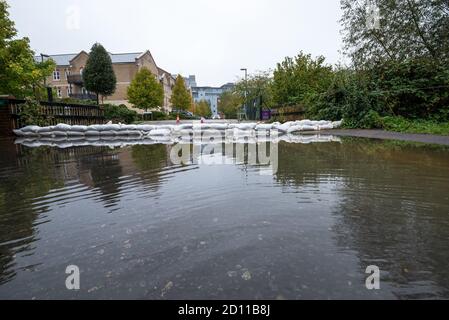 Aylesbury, Regno Unito. 4 ottobre 2020. Tempesta Alex inondazioni in Aylesbury, città della contea di Buckinghamshire. Un fine settimana di piogge quasi continue ha fatto scoppiare il Bear Brook sulle sue sponde, inondando le case di Southcourt’s Penn Road. Come la pioggia quasi continua sotparte i residenti iniziano ad accedere ai danni e iniziare a sgombrare. I servizi di emergenza erano presenti, bloccando l'accesso all'area allagata. Sacche di sabbia che tentano di trattenere l'acqua di inondazione dal Bear Brook. Credito: Stephen Bell/Alamy Foto Stock