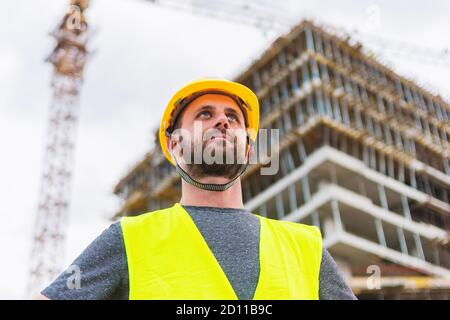 Un ingegnere che posa di fronte alla costruzione di un edificio è funzionamento di Foto Stock