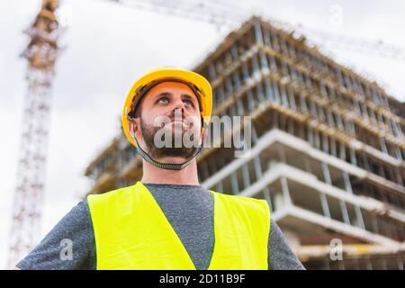 Un ingegnere che posa di fronte alla costruzione di un edificio è funzionamento di Foto Stock