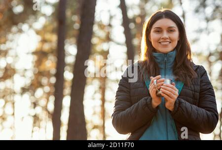 Bella ragazza sorridente zaino in spalla godendo il suo tè caldo Foto Stock