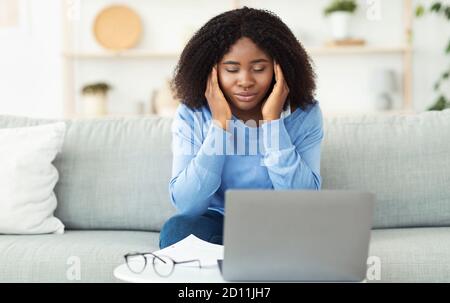 Stanca signora nera che tocca e massaggiando templi Foto Stock