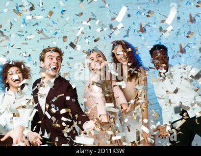 Happy Friends Faving Fun festa godendo di Falling Confetti Indoor Foto Stock