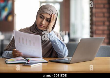 Una donna musulmana frustrato che lavora mentre si siede al bar Foto Stock