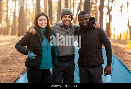 Amici avventurosi felici che posano sopra la tenda nella foresta Foto Stock