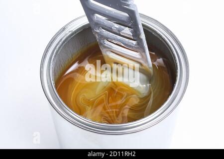 Un uomo che mescola vernice bianca in una lattina su uno sfondo bianco. Concetto di rinnovamento. Foto Stock