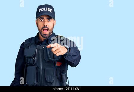 Giovane uomo ispanico che indossa uniforme di polizia che indica dispiaciuto e frustrato alla macchina fotografica, arrabbiato e furioso con voi Foto Stock