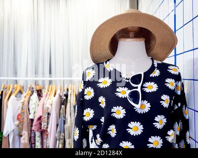 Manichini che indossano abiti estivi donna, camicia floreale, occhiali da sole e cappello di paglia vicino al portabiti in spogliatoio con spazio per la copia. Foto Stock