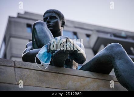 05 ottobre 2020, Berlino: Una maschera usa e getta sporca pende sulla mano di una figura della scultura 'Three Girls and a Boy' di Wilfried Fitzenreiter sulla Sprea. Foto: Annette Riedl/dpa Foto Stock