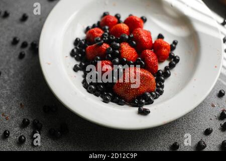 Ribes nero e fragole in piatto. Foto Stock