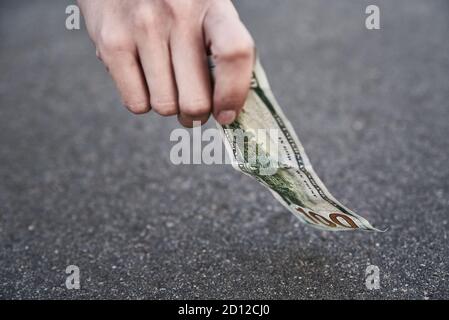 Prelevare a mano una banconota da cento dollari da terra. Trovato concetto di denaro Foto Stock