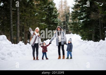 Padre e madre con due bambini piccoli nella natura invernale, camminando nella neve. Foto Stock