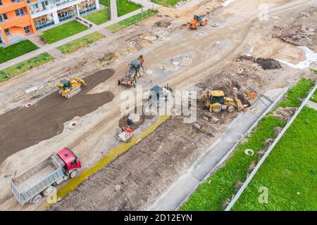 Costruzione di una strada urbana, posa di comunicazioni, installazione di botole fognarie, grondaie, cordoli. Preparazione per la pavimentazione, vista aerea Foto Stock