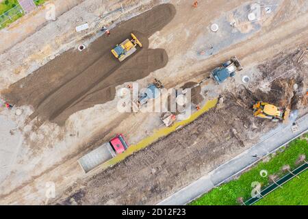 Costruzione di una strada urbana, posa di comunicazioni, installazione di botole fognarie, grondaie, cordoli. Preparazione per la pavimentazione, vista aerea Foto Stock