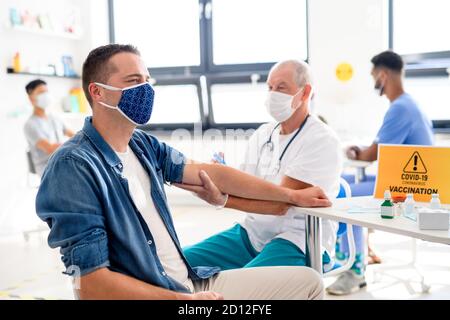 Uomo con maschera viso che si vaccina, coronavirus, covid-19 e concetto di vaccinazione. Foto Stock