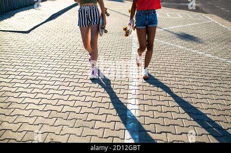 Ragazze adolescenti irriconoscibili amici con skateboards camminare all'aperto in città. Foto Stock