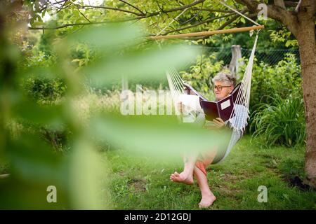 Ritratto di donna anziana attiva che lavora all'aperto in giardino, concetto di home Office. Foto Stock