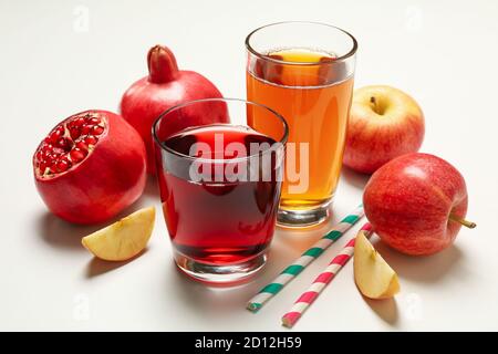 Bicchieri con succhi di mela e melograno su fondo bianco Foto Stock