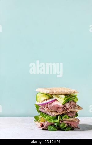 Manzo e verdure panini con affettati, Cetriolo, Insalata verde, segale grano intero pane in pila sul grigio verde pin-up sullo sfondo di stile. Foto Stock