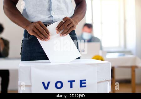 Irriconoscibile uomo afro-americano che ha messo il suo voto nel voto, elezioni usa e coronavirus. Foto Stock