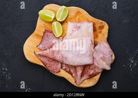 Vista dall'alto di calamari freschi non pelati grezzi sul taglio in legno scheda Foto Stock