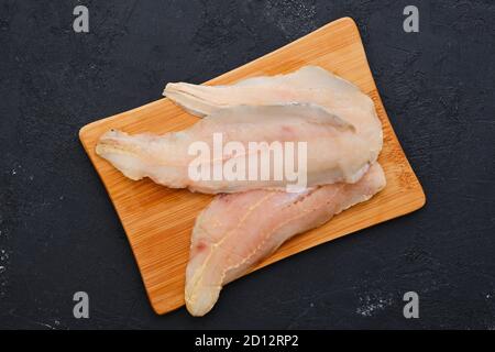Vista dall'alto del filetto di eglefino fresco crudo sul taglio in legno scheda Foto Stock