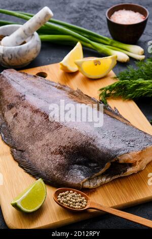 Halibut fresco grezzo senza testa su tagliere di legno Foto Stock