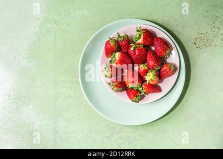 Fragole fresche sulla piastra di turchese su rosa pastello pin-up dello sfondo. Copia dello spazio. Vista superiore Foto Stock