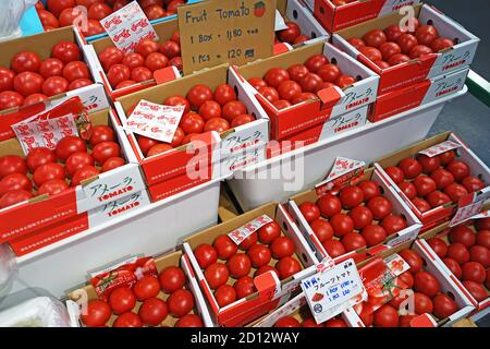 Pile di scatole di carta di frutta di pomodori esposte sullo scaffale Foto Stock