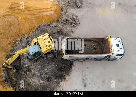 l'escavatore carica sabbia nella vista dall'alto di un camion. Foto Stock