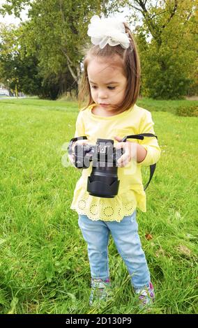 Un bambino con fotocamera professionale scatta foto all'esterno sullo sfondo del parco Foto Stock