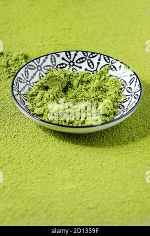 Il tè verde Matcha in polvere in vaso in ceramica oltre la polverizzazione di matcha come sfondo. Close up Foto Stock