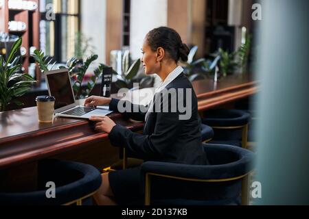 Giovane donna attenta seduta davanti al suo laptop Foto Stock